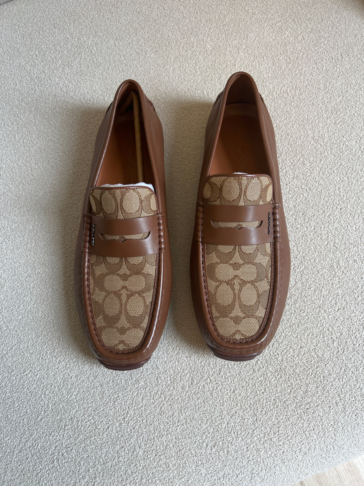 Coach men's loafers are the Liam Driver model, featuring a distinctive signature jacquard canvas panel contrasted with solid leather