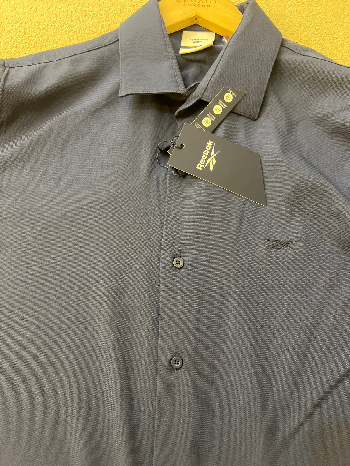 Reebok brand shirt is a navy blue long-sleeved garment featuring a slim fit and a classic collar
