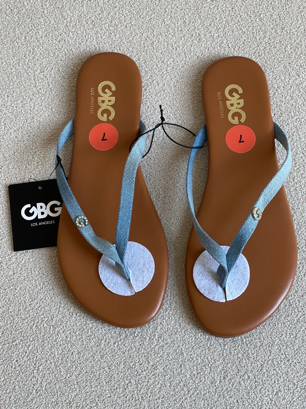 GBG Los Angeles sandals feature a light blue denim strap and a tan footbed