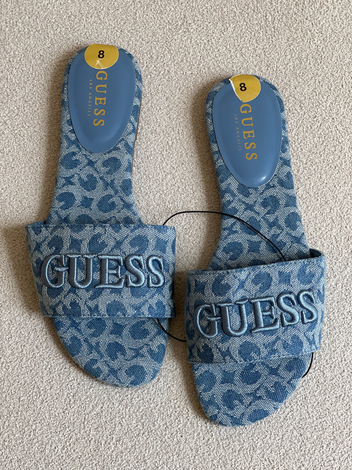Guess brand sandals feature a distinctive denim-style fabric with a patterned finish and an embossed logo