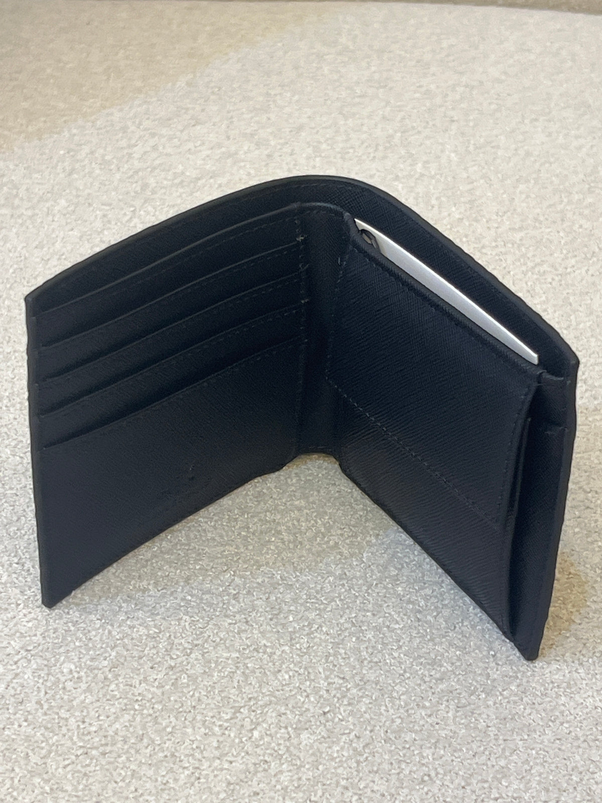 Armani Exchange bifold wallet, likely model 958098_CC838, featuring an all-over embossed logo design in black