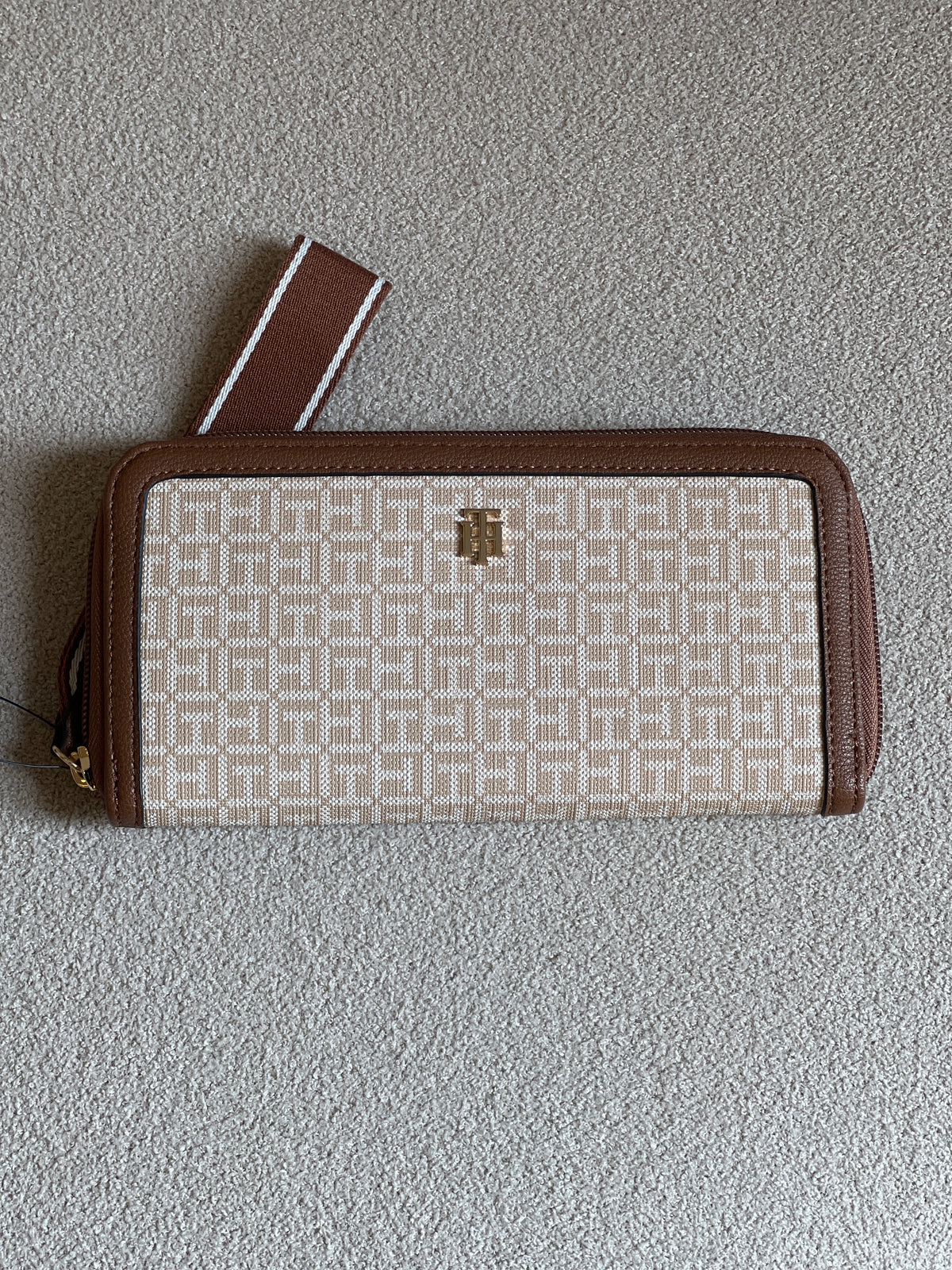 Tommy Hilfiger monogram jacquard zip-around wallet features a classic beige pattern with brown trim