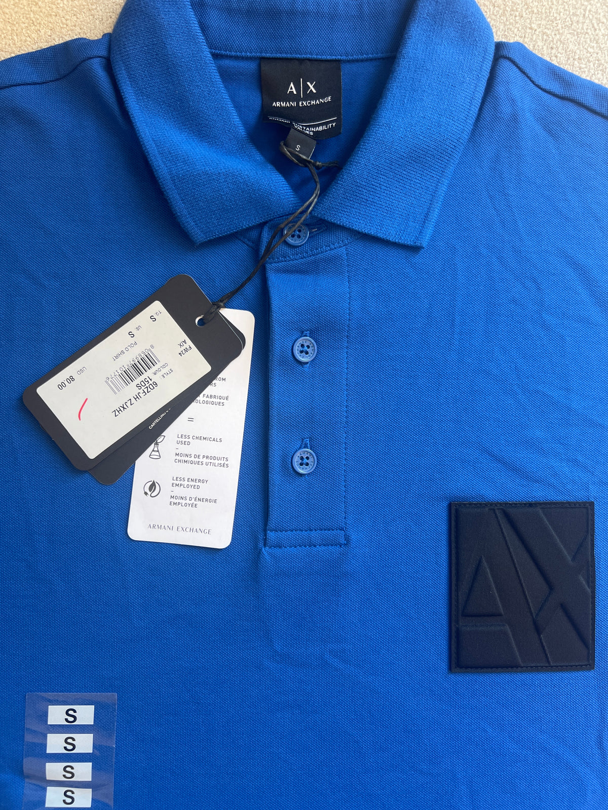 The Armani Exchange ASV Organic Cotton Regular Fit Polo with Logo is a blue men's polo shirt featuring an embossed logo patch