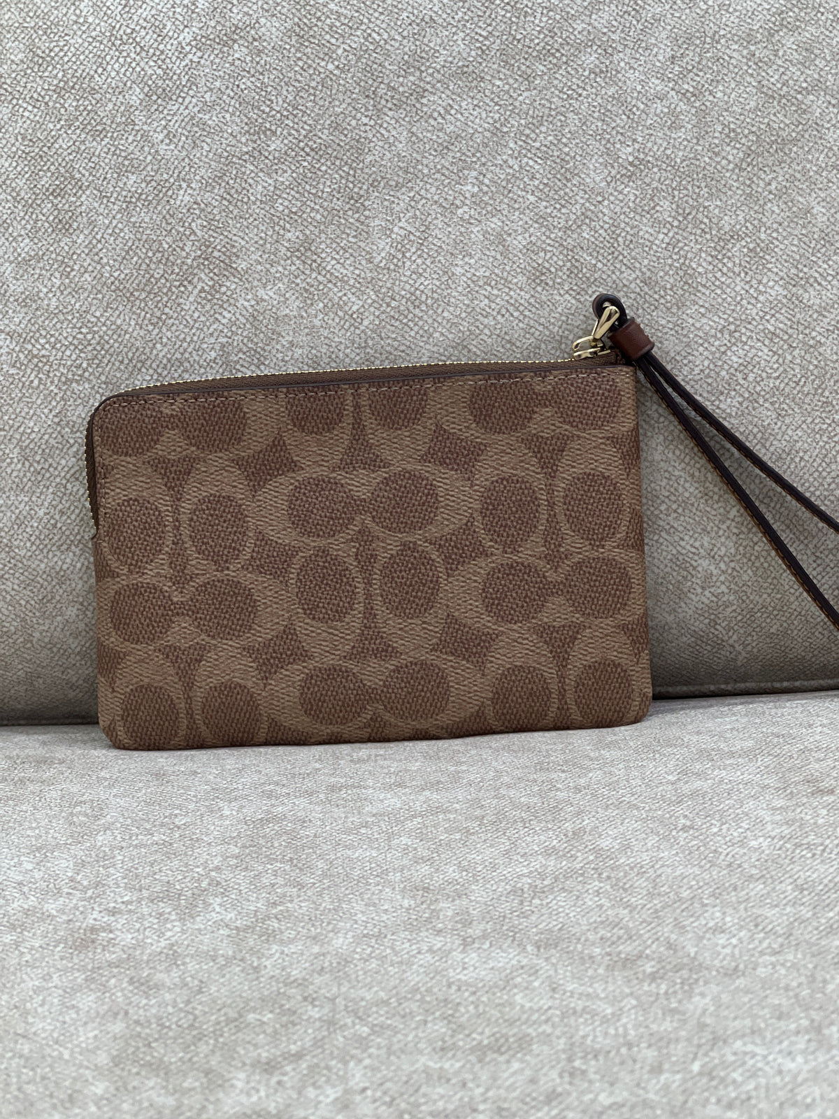Coach Corner Zip Wristlet in signature canvas with a brown leather stripe