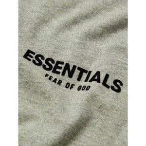 Fear of God Essentials t-shirt in a grey colorway, potentially "Light Oatmeal" or "Dark Oatmeal